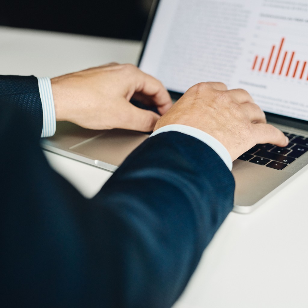 Mann tippt auf Laptop mit Chart